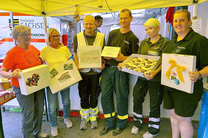 Sigrid Blumenbach und Irene Hentzschel von den Neustädter Gymnastikfrauen mit Einsatzkräften bei der Übergabe der Kuchen